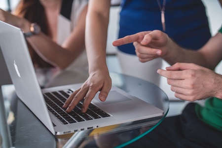 Image of people working together on a laptop.