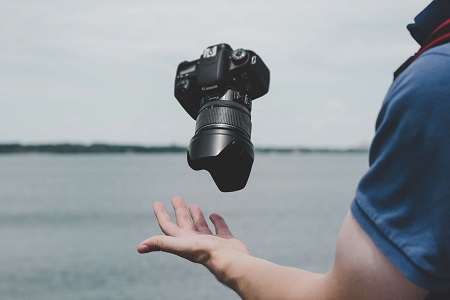 Image of a camera floating in the air above a person's hand.