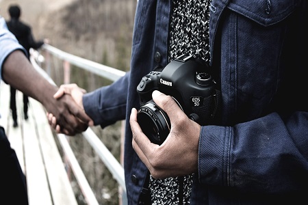 Image of a person with a camera shaking hands with another person.